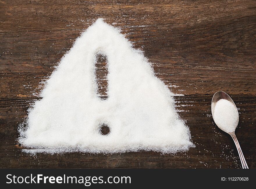 Sign of warning attention made of granulated sugar. A conceptual photo illustrating the harm from consuming white refined sugar and products containing it. Sign of warning attention made of granulated sugar. A conceptual photo illustrating the harm from consuming white refined sugar and products containing it