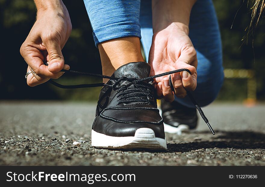 Fitness girl is tighting up sport shoe outdoors before work out. Fitness girl is tighting up sport shoe outdoors before work out