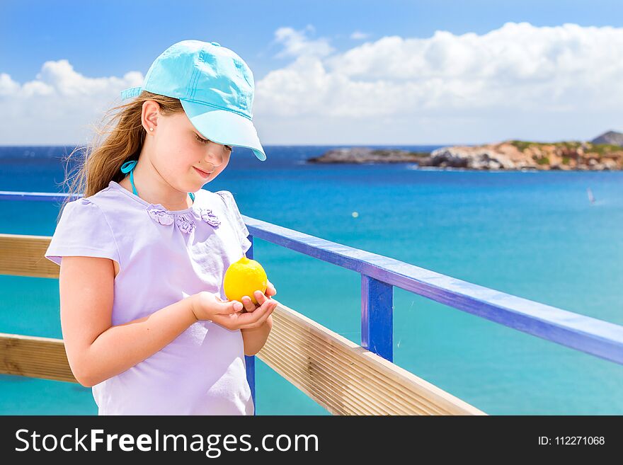 Girl with lemon posing against Cretan sea. Bali