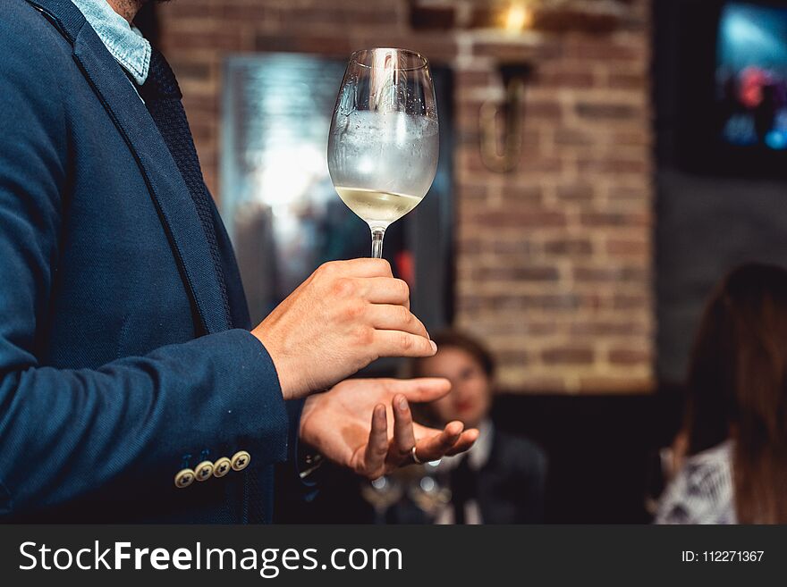 Wine tasting in a restaurant. man in a blue suit holds glass of white wine