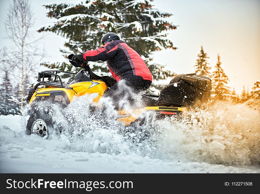 A man is riding an ATV in winter on the snow in his helmet. A man is riding an ATV in winter on the snow in his helmet.