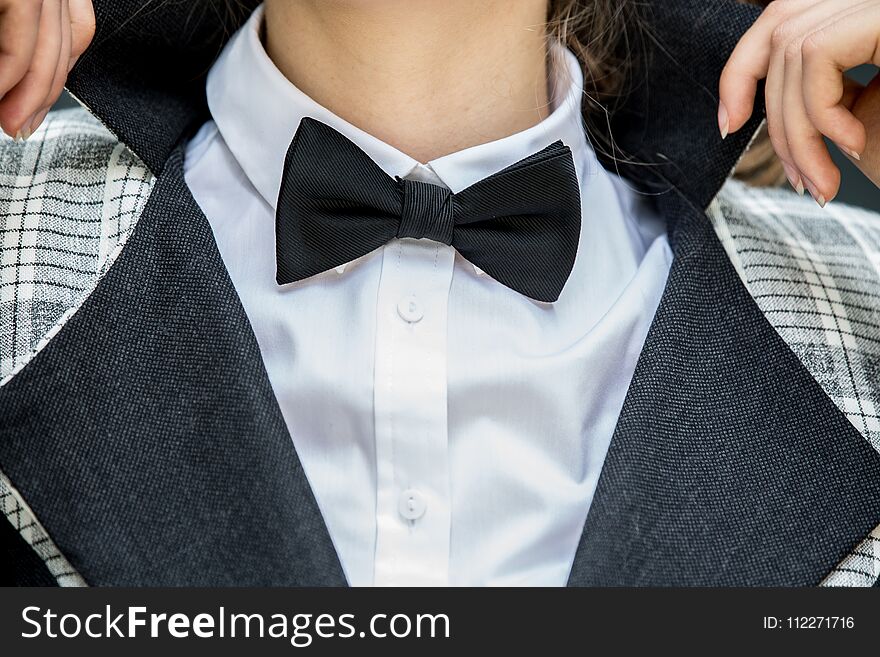 Close up of young Woman holding her collar in white shirt and black and gray jacket and a black bow tie