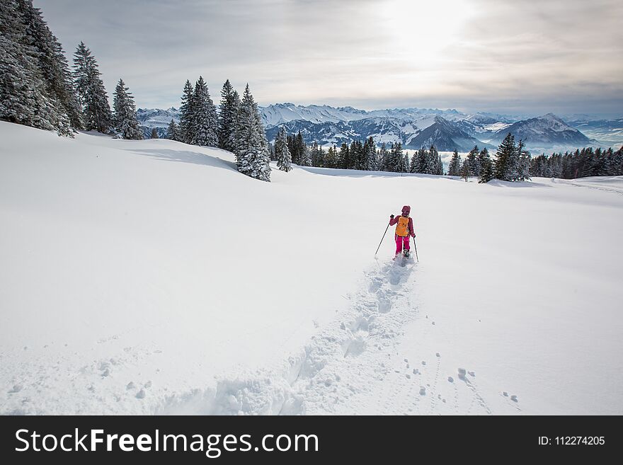 Pretty, young woman snowshoeing in high mountains