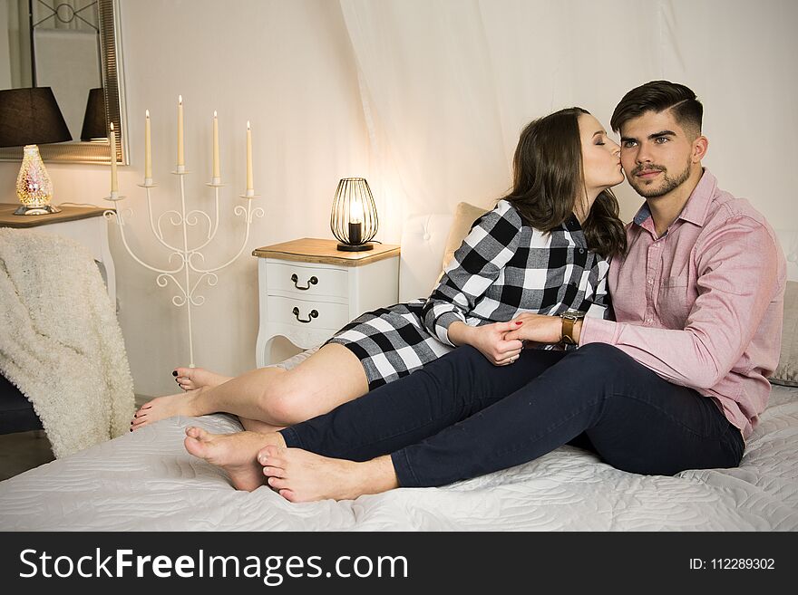 Young couple in love sitting on a bed at home. Young couple in love sitting on a bed at home