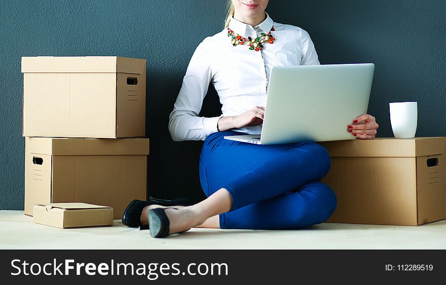 Woman Sitting On The Floor Near A Boxes With Laptop