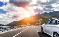 A White Car Rushing Along A High-speed Highway In The Sun. Stock Photo A White Car Rushing Along A High-speed Highway In The Sun. Stock Photo