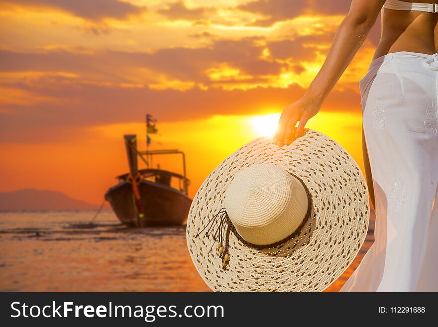 Woman resting on the beach at sunset wearing a white sarong and