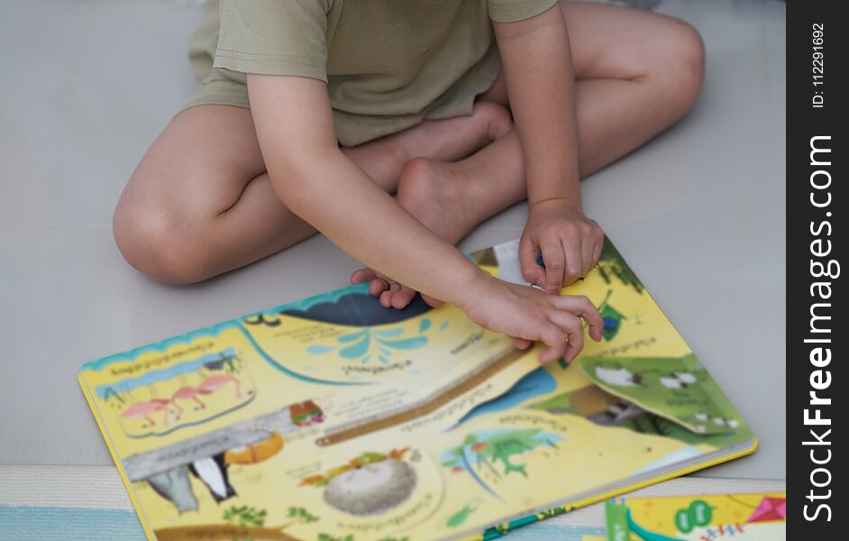 Boy sit on floor,reading colourful book in home school or learning concept