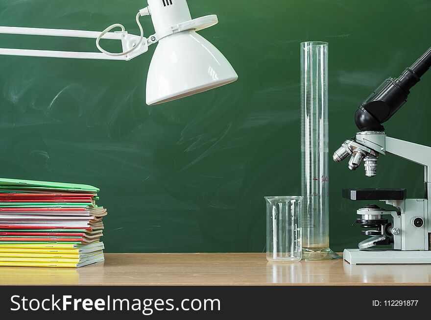 Teacher, student, biologist or chemist desk table. Education background with copy space. Education concept. Microscope, vial, flask, beaker and stacked books on the table. Teacher, student, biologist or chemist desk table. Education background with copy space. Education concept. Microscope, vial, flask, beaker and stacked books on the table.