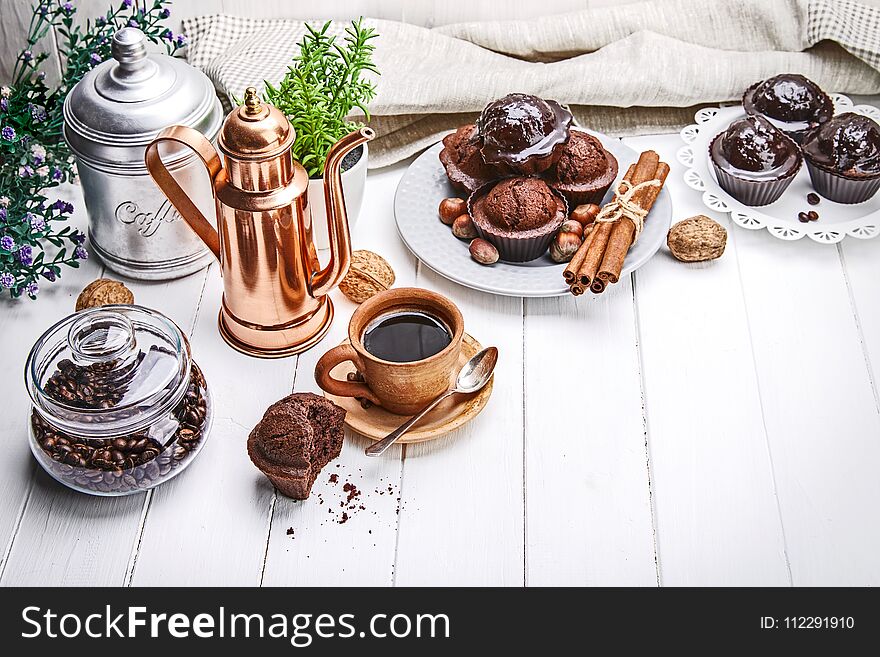 Coffee in clay cup with chocolate muffin on white wooden board in rustic style.