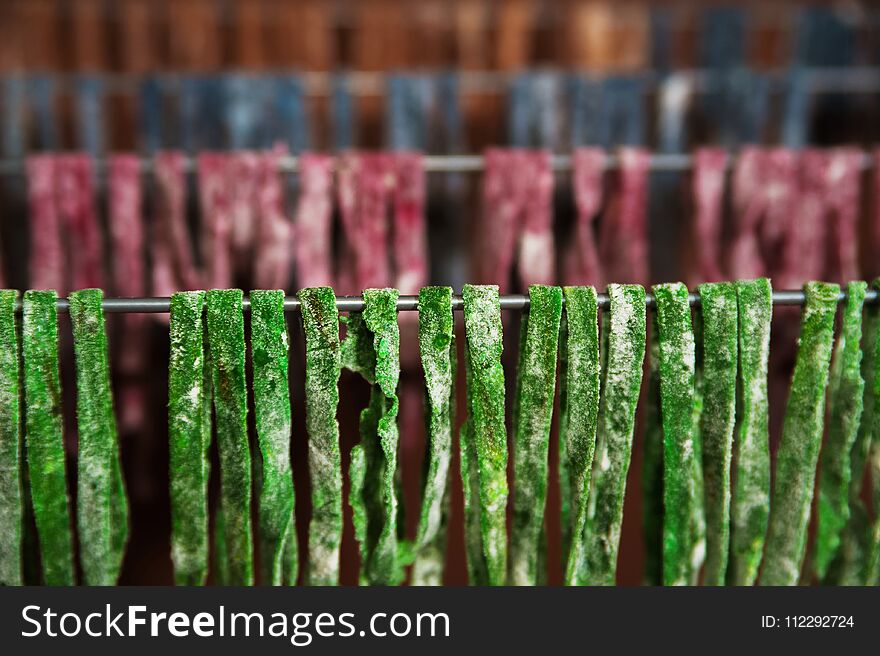 The homemade pasta paste is dried on the dryer. Green, red, blue, yellow fettuccine dries, textural background from pasta