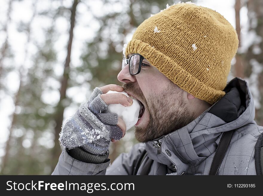 A Bearded Man Eats A Snowball In The Forest With Pleasure.