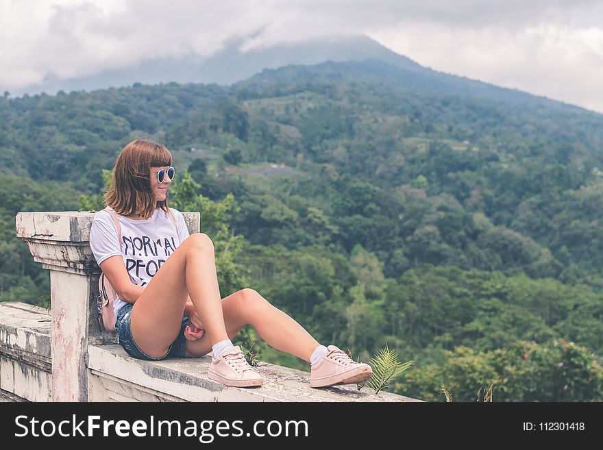 Woman in White Shirt and Blue Denim Short Shorts Sitting