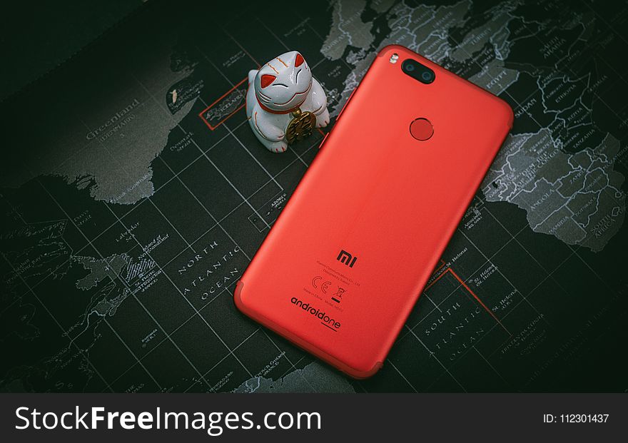 Red Xiaomi Mi Smartphone Beside White Cat Figurine