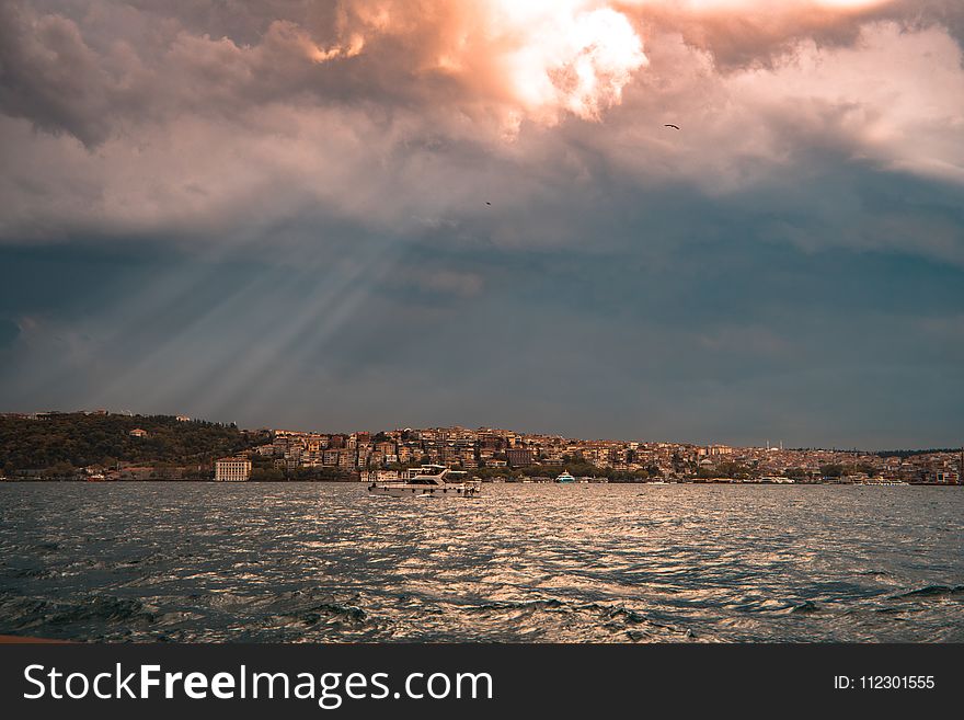 Concrete Buildings Near Sea Under White and Blue Cloudy Sky