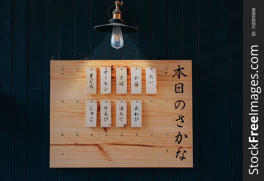 Kanji Printed Tags Hanged on Brown Wooden Board Lighted by Pendant Lamp