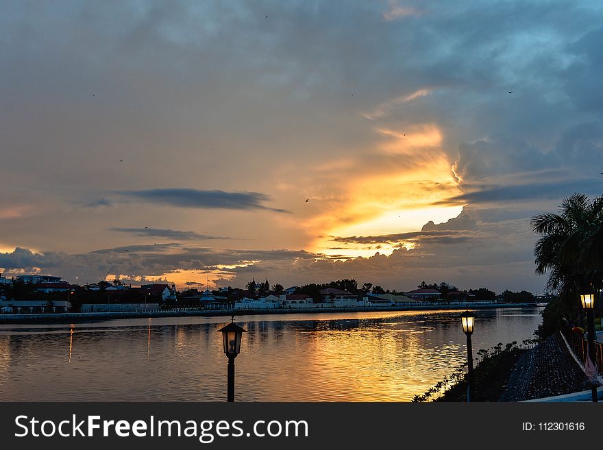 Lamppost Near Body Of Water At Golden Hour