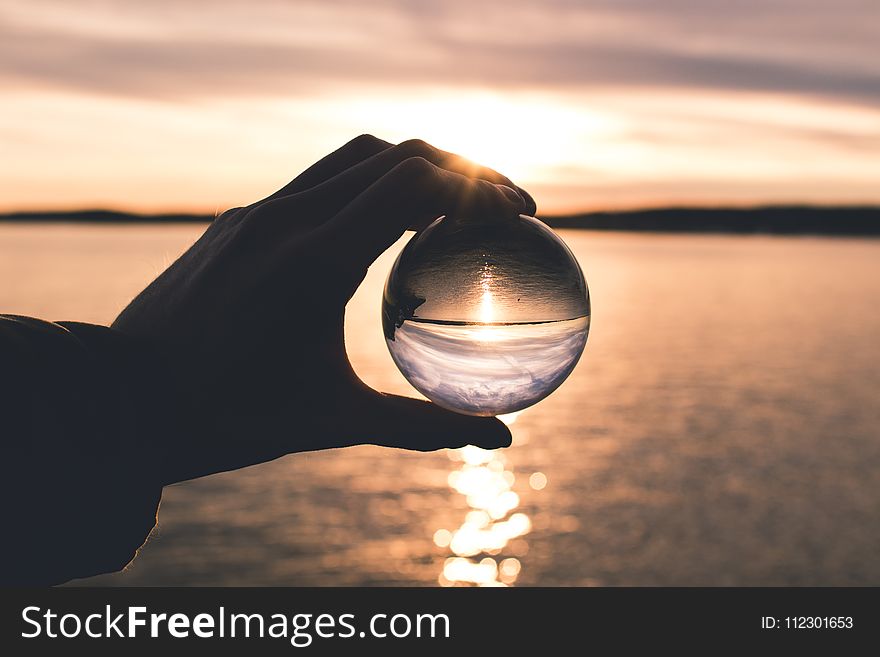 Photo Displays Person Holding Ball With Reflection Of Horizon