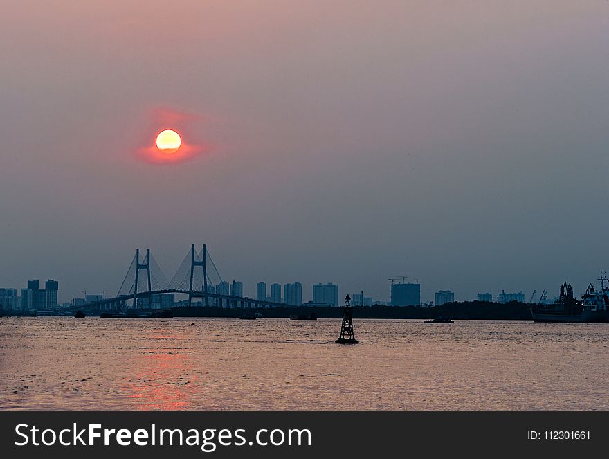 Ship Near Brown Bridge Across Sea during Sunset