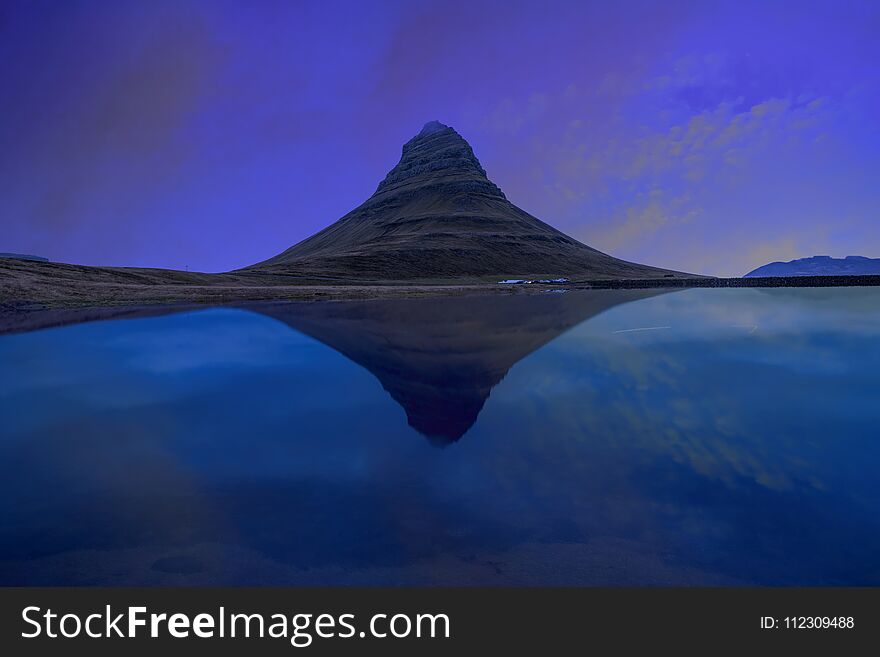 Kirjufell mountain with water reflection in the lake during sunset