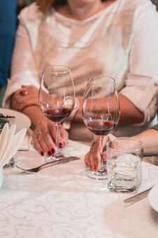 Woman Holds Glass Of Red Wine. People Consider The Color Of The Wine And Try How It Smells In Different Glasses Royalty Free Stock Image