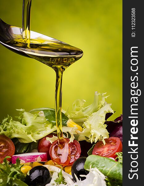 Fresh mixed salad topped with a drizzle of olive oil on a green background. Fresh mixed salad topped with a drizzle of olive oil on a green background