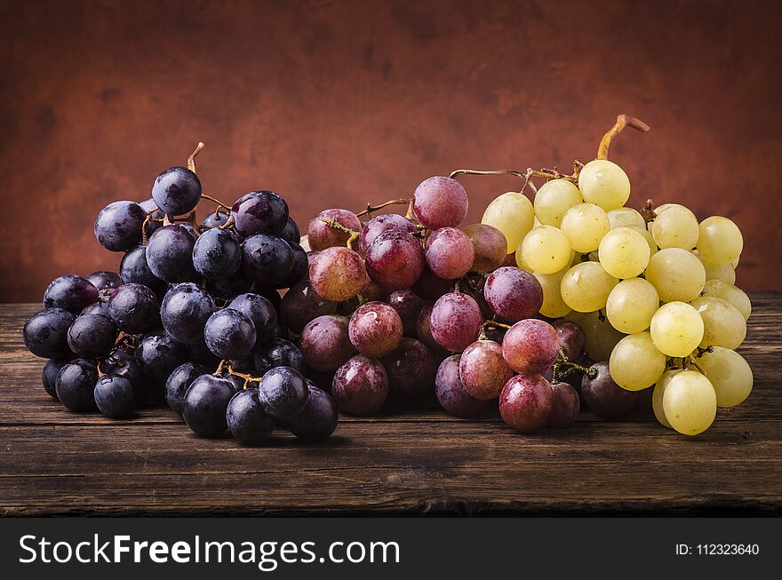 Bunches of grapes of different types on a rough wooden table. Bunches of grapes of different types on a rough wooden table