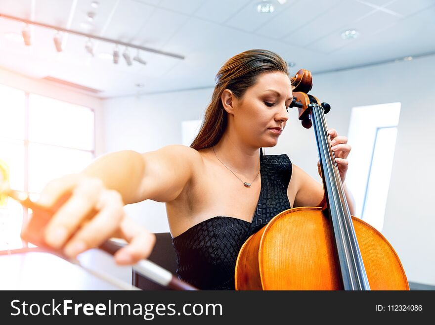 Young smiling woman playing cello