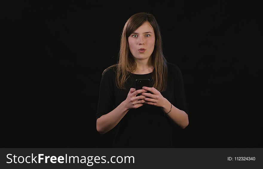 A Lady Using a Phone Against a Black Background