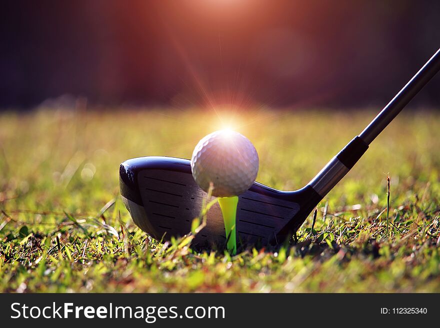 Blurred golf club and golf ball close up in grass field with sun