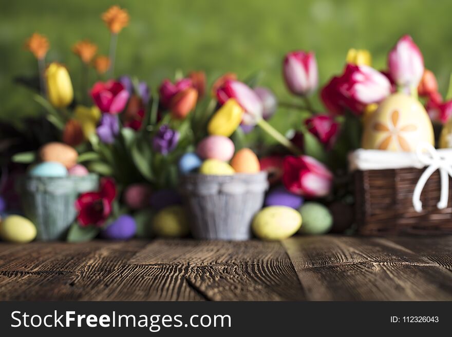 Easter eggs and tulips on wooden rustic table. Blue bokeh background. Easter eggs and tulips on wooden rustic table. Blue bokeh background.