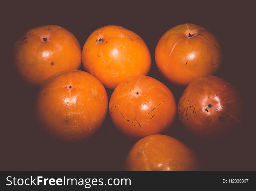 Delicious ripe persimmon, juicy orange fruits on black background, filtered. Delicious ripe persimmon, juicy orange fruits on black background, filtered.