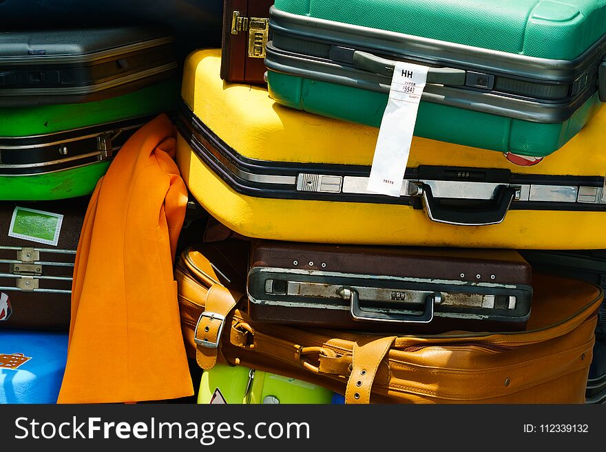 Close up of pile of old travel suitcases luggages stacked for transport one above the other in many colors piled up together.