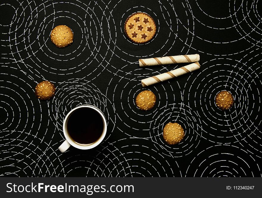 Coffee, sweet biscuits on a black background with concentric circles. Coffee, sweet biscuits on a black background with concentric circles