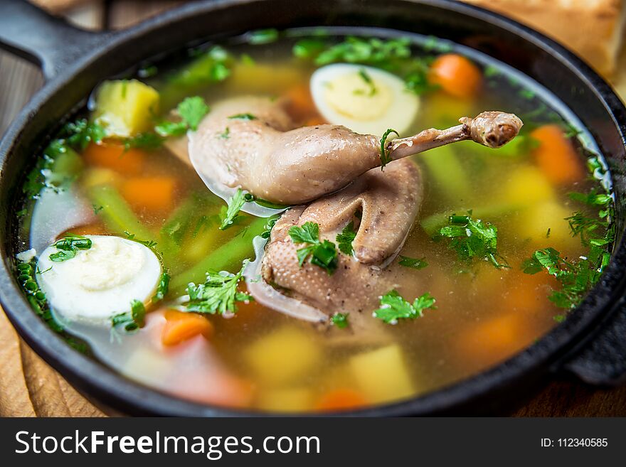 Soup with quail meat, with quail eggs and vegetables, in a frying pan