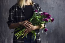 Young Woman In Plaid Shirt Holding Bouquet Of Purple Terry Tulips Stock Photo
