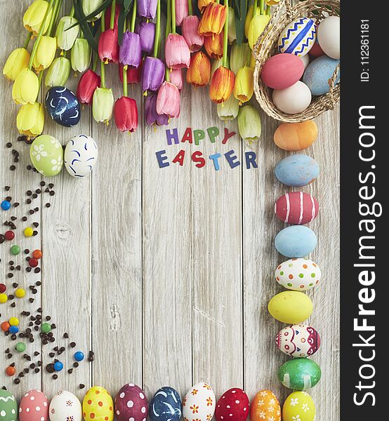 colorful easter eggs and tulips on old white wooden board, minimal, flat lay