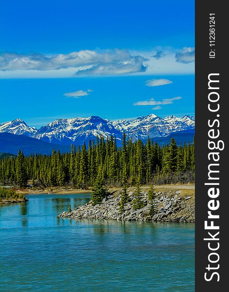 The north Saskatchewan river meanders along the rocky shoreline with mountains in the background. The north Saskatchewan river meanders along the rocky shoreline with mountains in the background