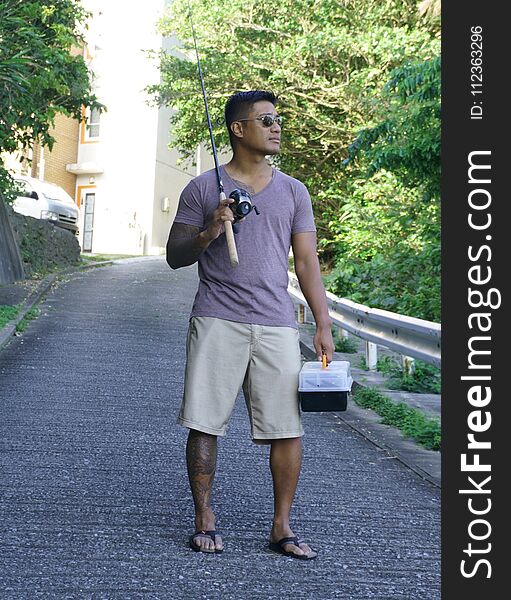 Man on seawall on vacation in Japan with T shirt going fishing. Man on seawall on vacation in Japan with T shirt going fishing