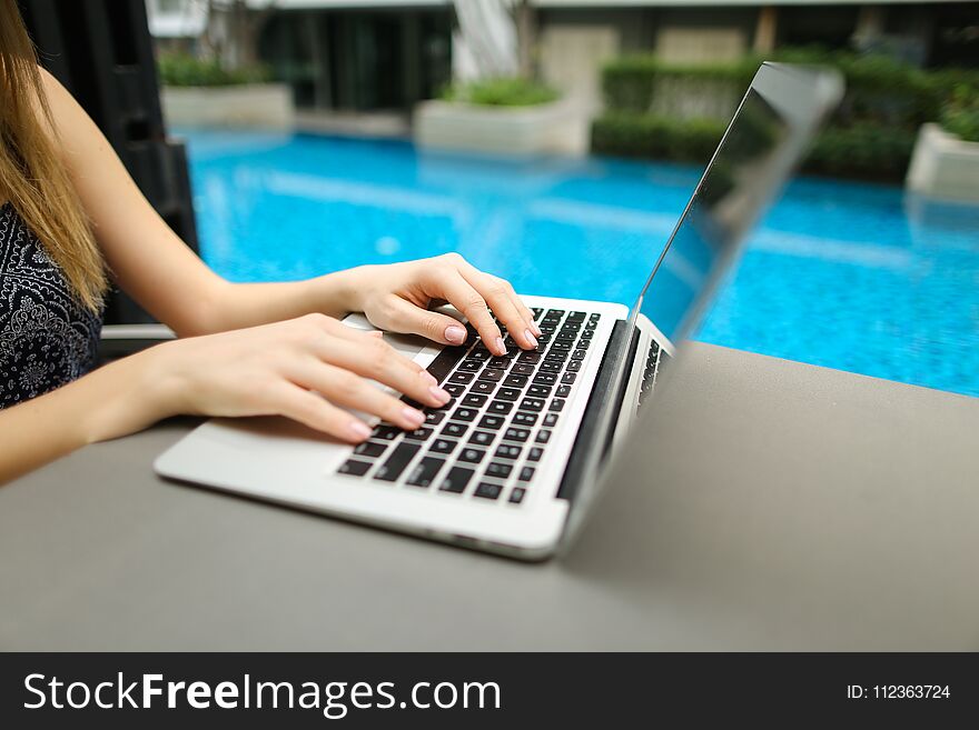 Woman Fingers typing on computer keyboard. Close up portrait of hands pressing buttons on laptop at sunny day swimming pool. concept of business freelance working, new technologies. Woman Fingers typing on computer keyboard. Close up portrait of hands pressing buttons on laptop at sunny day swimming pool. concept of business freelance working, new technologies