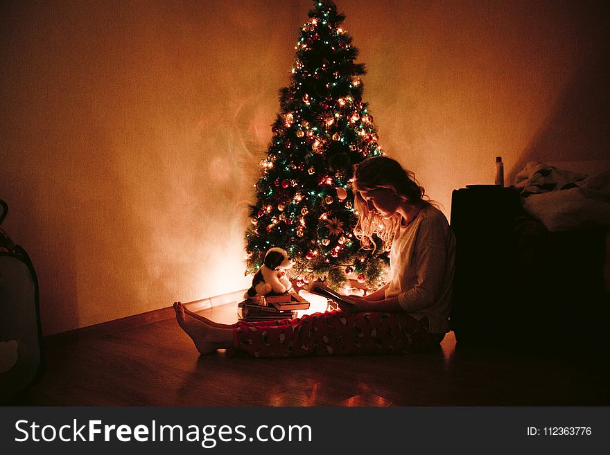 Photo of Woman Sitting Near the Christmas Tree