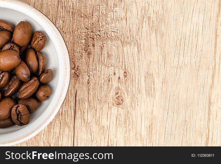 Coffee Beans on White Ceramic Bowl on Top of Brown Wooden Surface