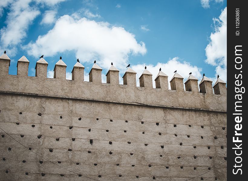 Brown Concrete Castle Wall Under Cumulos Clouds