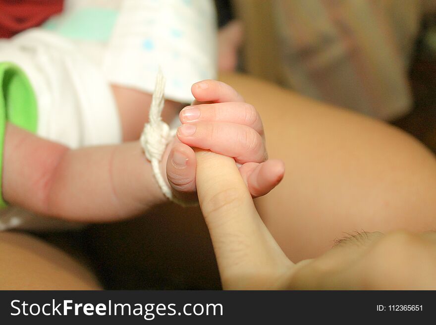 Infant holding father`s finger. 2 months old baby holding his dad `s left little finger. First love. Really true love. Happy family.