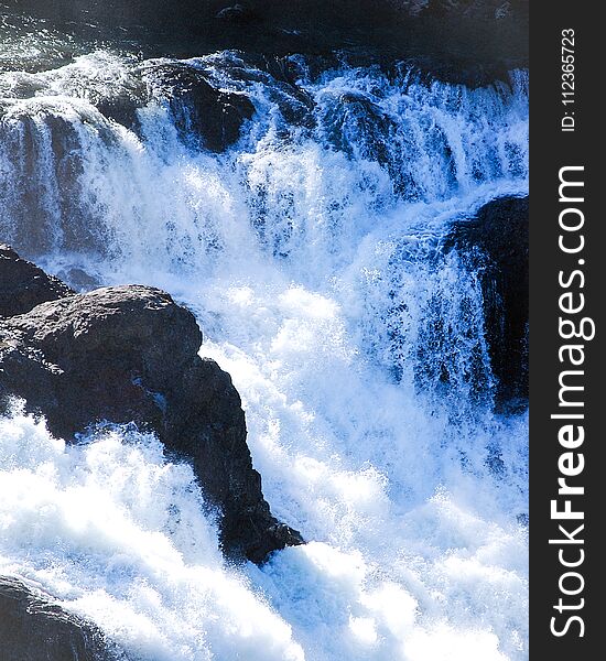 A small waterfall cascading through large boulders on it`s way to the ocean. A small waterfall cascading through large boulders on it`s way to the ocean