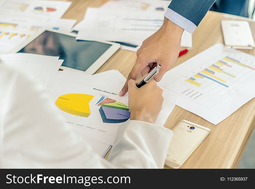 Close-up of business team image of male hand pointing at business document during discussion at meeting and using pen with financial diagram and digital tablet