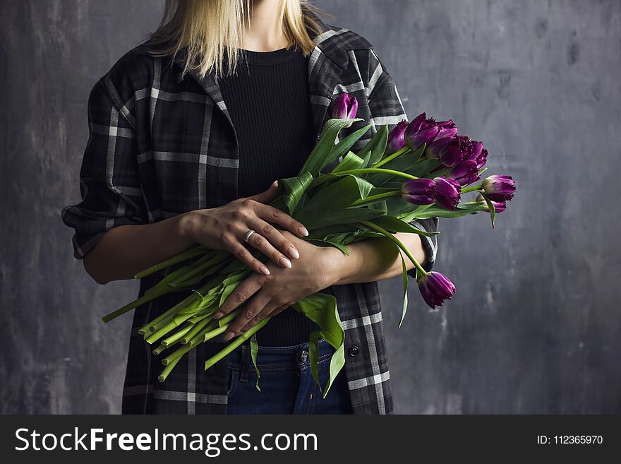 Young woman in plaid shirt holding bouquet of purple terry tulips