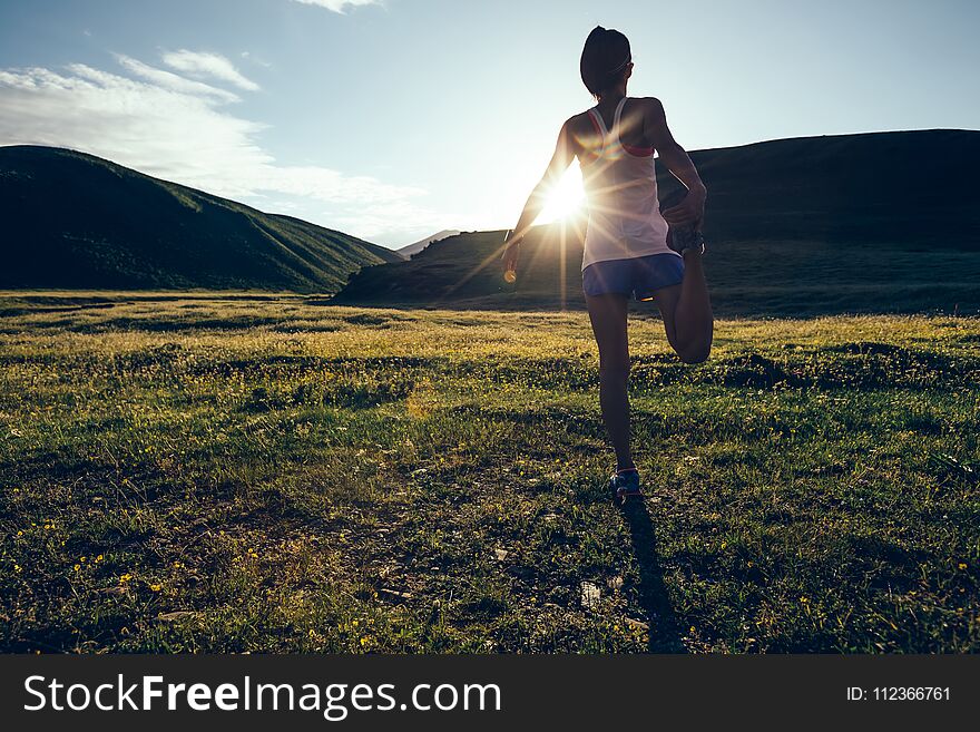 Runner warming up on sunset grassland trail