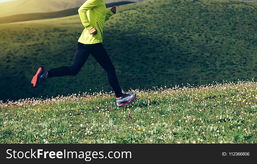 Fitness woman runner running on mountain grassland