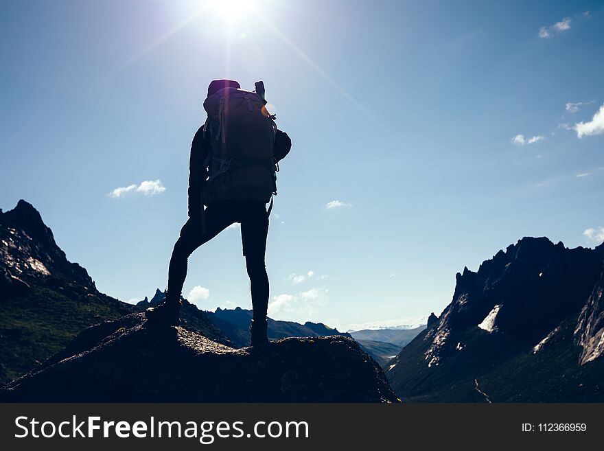 Woman with backpack hiking on sunrise mountain top